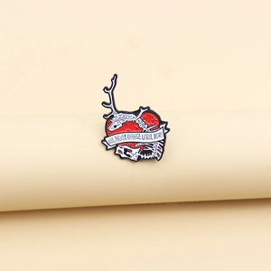Broche gothique en émail avec cœur rouge, crâne et ruban sur fond beige minimaliste
