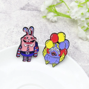 Cartoon rabbit and multi-eyed monster enamel pin set on a white ceramic plate