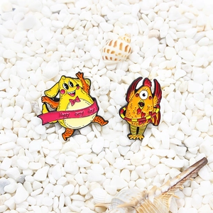 Broches émaillées coq et créature jaune sur pierres blanches et coquillages