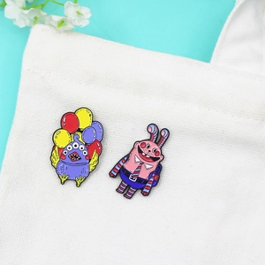 Creative cartoon enamel brooches featuring a purple monster and a pink rabbit on a bag