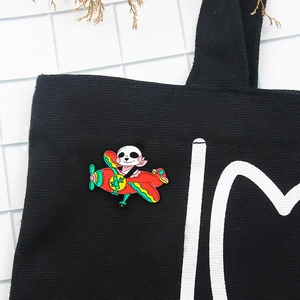 Detail of cute panda pilot enamel pin pinned on a black canvas bag accessory