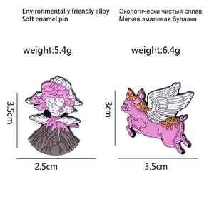 Cartoon enamel pins set featuring a pink winged flying pig and an erupting volcano badge