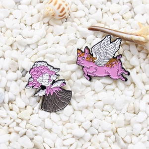 Creative enamel pin set featuring a flying pink pig and an erupting volcano on white stones