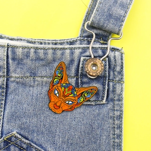 Sphynx cat enamel brooch with geometric patterns on a denim jacket background