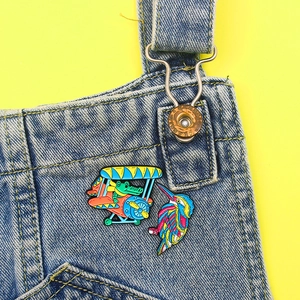 Cartoon crocodile in airplane and colorful bird enamel pins on denim pocket background