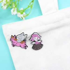 Creative flying pig and erupting volcano enamel pin set on a white canvas bag