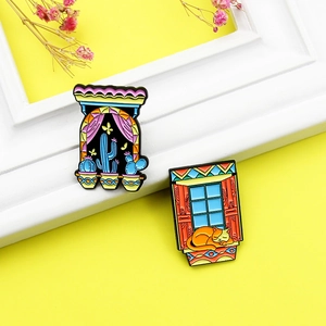 Detail of colorful enamel pins featuring a sleeping cat and cactus on a yellow background