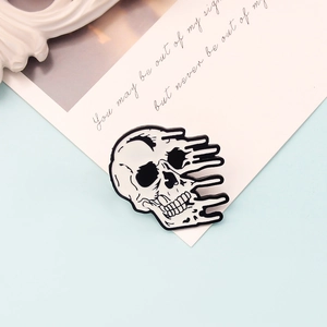 Détail d'un pin's en émail crâne fondu noir et blanc sur une carte décorative