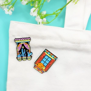 Enamel pin set featuring a blue cactus and sleeping orange cat on a white canvas bag