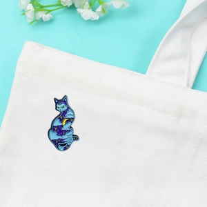 Starry sky and moon cat enamel brooch pinned on a white canvas bag with a blue background