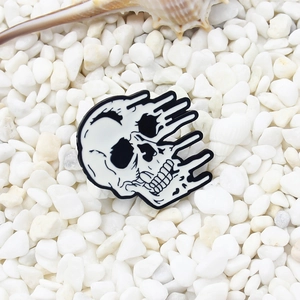 Épingle en émail crâne fondu style punk sur fond de pierres blanches avec coquillage