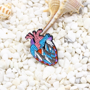 Creative anatomical heart enamel brooch with iceberg design on white pebble background