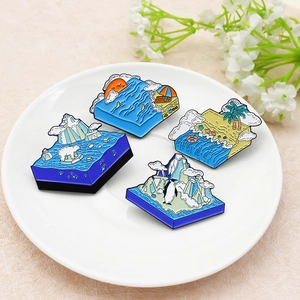 Set di quattro spille in smalto a tema naturale con paesaggi artici e tropicali su vassoio