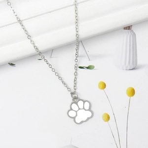 Minimalist silver animal paw pendant necklace with white enamel inlay on a floral background