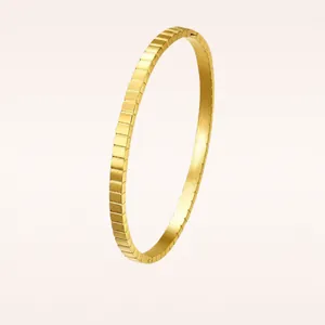 Close-up of gold stainless steel bangle with a minimalist square grid ice cube design