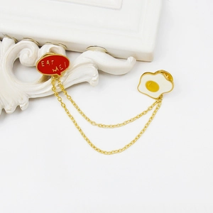 Creative fried egg and EAT ME speech bubble chain brooch with polished golden finish