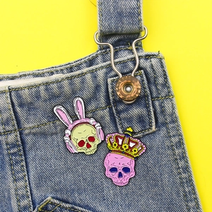 Gothic rabbit ear headset and crown skull enamel pins on blue denim overalls