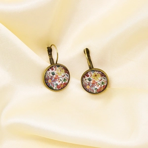 Detailed view of vintage floral drop earrings on yellow satin with bronze metal frame