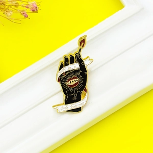 Broche en émail main avec allumette allumée sur fond jaune avec fleurs séchées