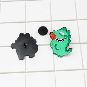 Cartoon green fire-breathing dinosaur enamel pin with a black rubber clutch backing