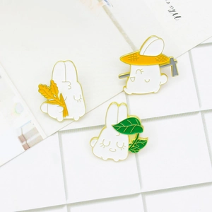 Three-piece set of cute enamel bunny pins with farming and leaf nap themes on white grid