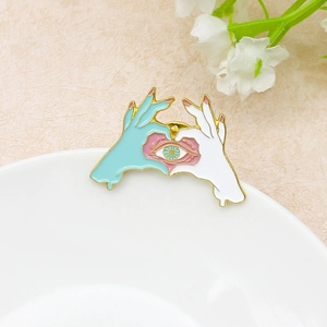 Enamel heart hand pin with realistic eye detail and polished gold-plated edges