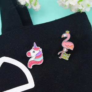 Enamel unicorn and flamingo brooch set pinned on a black canvas bag for fashion decor
