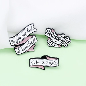 Three-piece enamel pin set with inspirational quotes on ribbons and a pink heart design