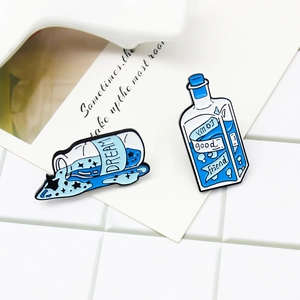 Blue enamel dream bottle and ribbon friend pins set on minimalist grid background