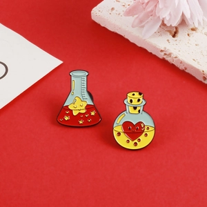 Dettaglio di spillette in smalto con una stella in un pallone e cuore in una fiala