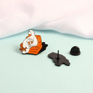 Macro detail of cartoon goose enamel pin with orange sofa and black rubber backing