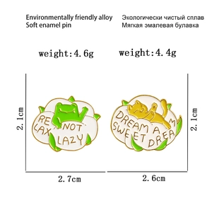 Detailed view of cartoon enamel pins featuring a green frog and yellow cat on cotton base