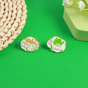 Detail of cartoon frog and cat enamel pins with Dream a Sweet Dream and Relax Not Lazy text