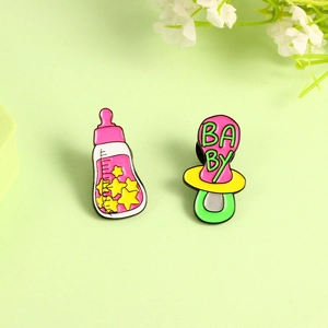 Set aus Babyfläschchen und Schnuller-Emaille-Pins mit Baby-Schriftzug auf grünem Grund