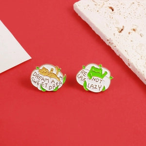 Detail of enamel frog and cat pins with Dream a Sweet Dream and Relax Not Lazy text