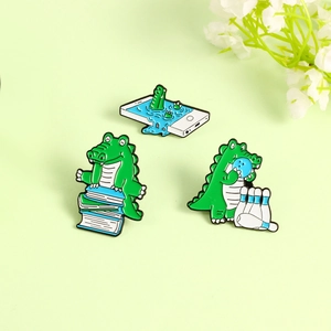 Detailed view of three cute green crocodile enamel pins on a light green background