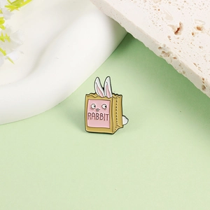 Cute cartoon rabbit enamel pin in a paper bag on a minimalist decorative stone base
