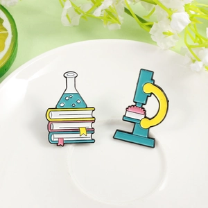 Enamel pin set featuring microscope and chemistry flasks on books for science lovers