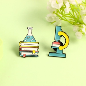 Science enamel pin set with blue microscope and laboratory flask on stacked books