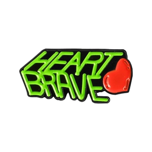 Black enamel brooch with green Heart Brave lettering and a small red heart accent
