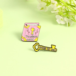 Enamel book and key brooch set with floral details and Explore the World text