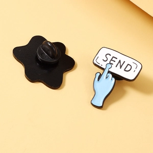 Detail showing the SEND button enamel pin with its black rubber back clasp attachment