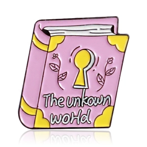 Pink book-shaped enamel brooch with yellow keyhole and The Unknown World text