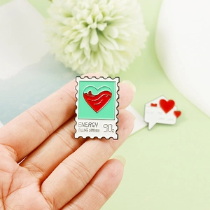 Detail of light green enamel stamp pin with red liquid heart and Energy Filling Station text