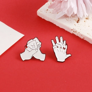 Detail of creative hand-holding enamel brooches with white finish and red nails