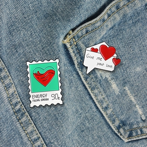 Creative enamel heart stamp and envelope lapel pins pinned on blue denim fabric