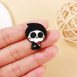 Close-up of cute chibi Grim Reaper enamel pin with red rose held by fingers
