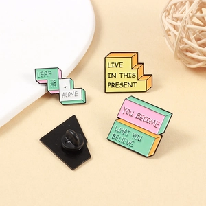 Pastel enamel pins with motivational quotes like Live In This Present and Leaf Me Alone