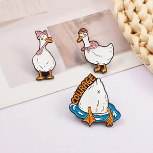 Detailed view of three cute enamel duck pins including diving duck with Courage text