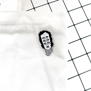 Détail du pin's émaillé surréaliste Edgar Allan Poe sur un sac en toile blanche